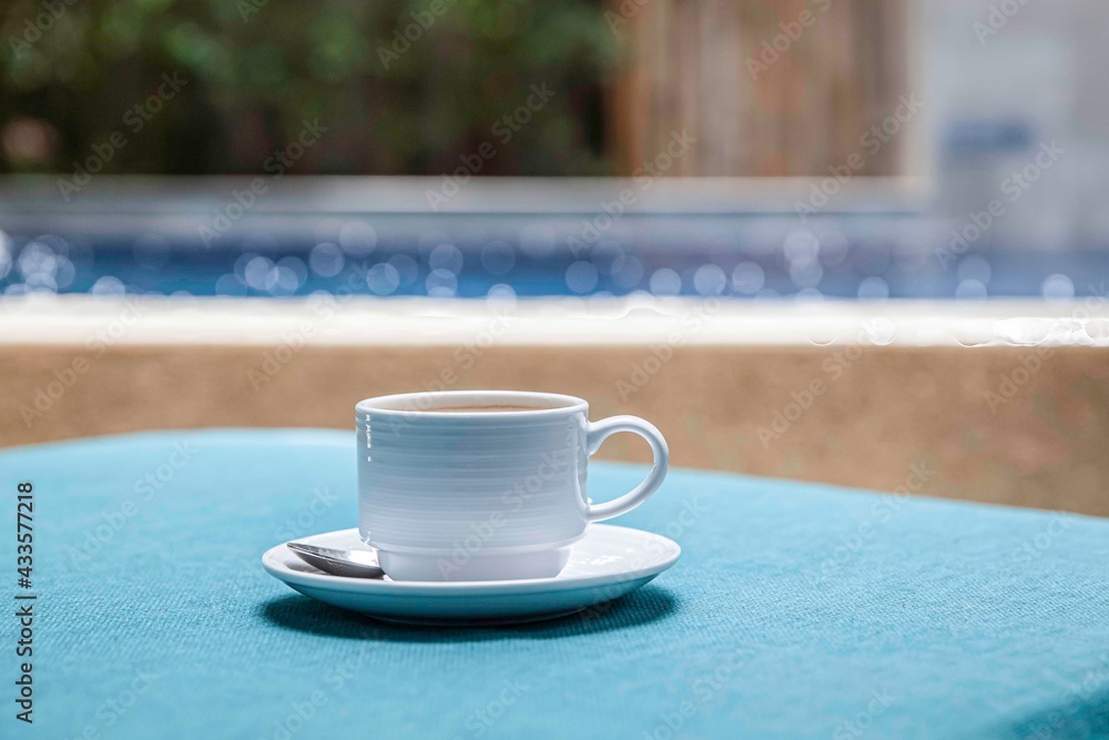 The coffee mug placed on the table has a blue tablecloth - obrazy, fototapety, plakaty 
