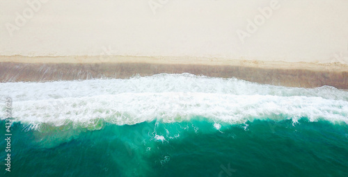Top view of beautiful dreamy beach. Beautiful waves covering sandy beach. Travelling destination.Aerial view
