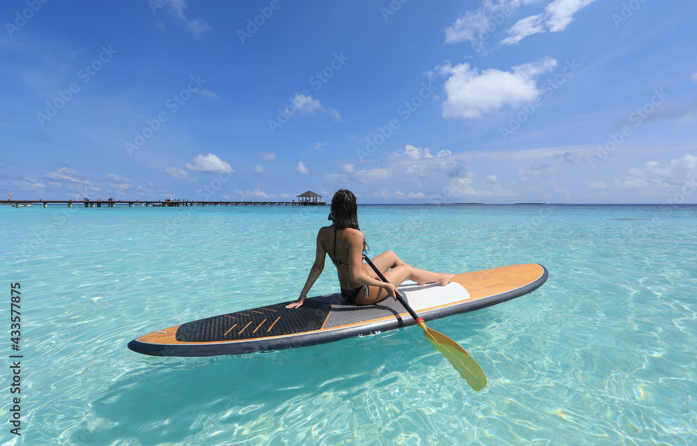 sports girl with paddle on surfboard in the Ocean, Maldives