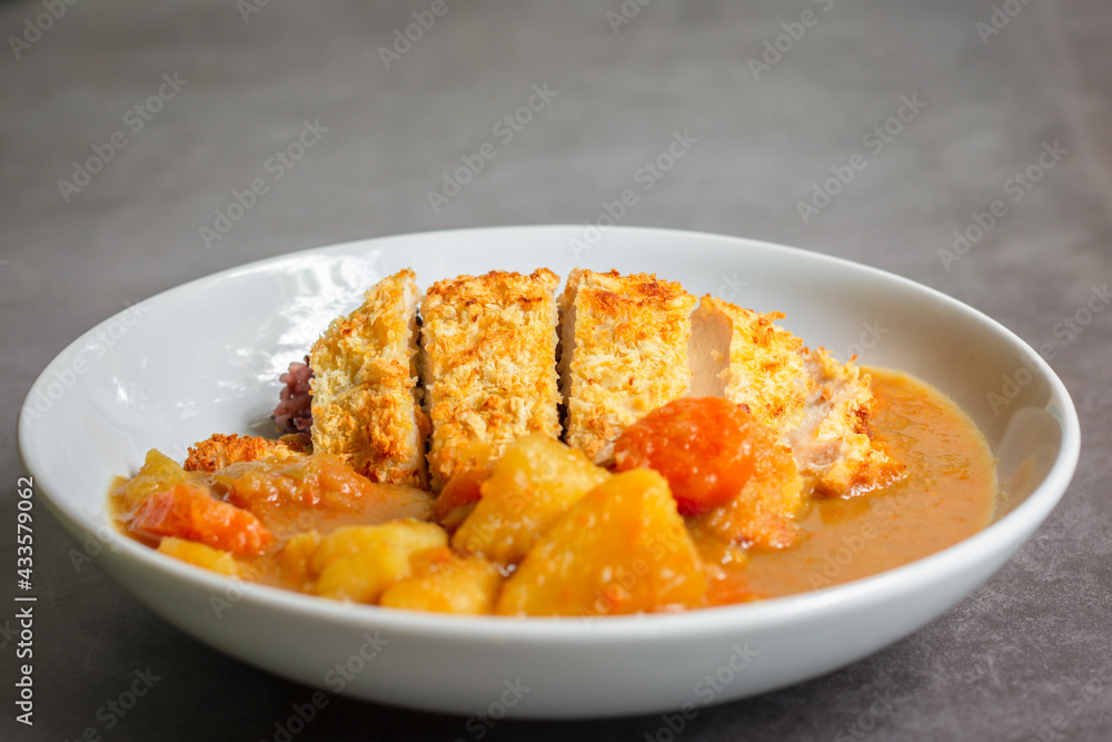 Japanese curry with rice, carrot, potato and deep fries chicken in white dish on table. Japanese curry with rice, carrot, potato and deep fries chicken in white dish on table.