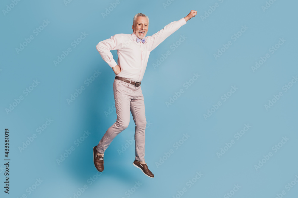 Full length view of handsome man jumping up having fun isolated blue background Full length view of handsome man jumping up having fun isolated blue background