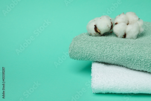 Clean folded towels and cotton on mint background