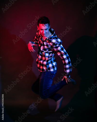 A guy in a plaid shirt with red and blue lighting in the studio on a black background