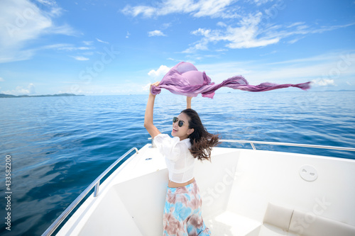 excited tourist enjoying and relaxing on speedboat with a beautiful view of ocean and mountain in backgound © tonefotografia