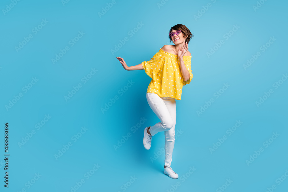 Full body photo of charming happy positive girl dance look empty space wear coll glasses isolated on blue color background Full body photo of charming happy positive girl dance look empty space wear coll glasses isolated on blue color background