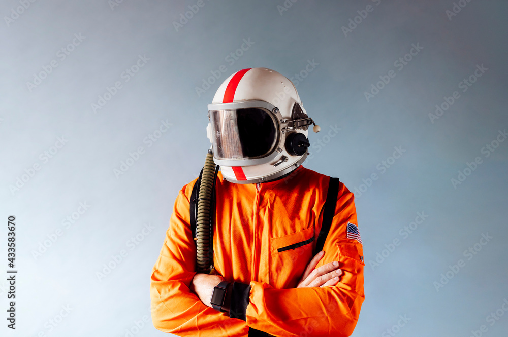 Caucasian man in orange protective suit with arms crossed, looking surprisingly sideways at the stars. Isolated blue background