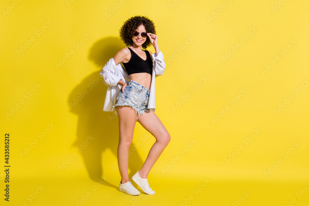 Photo of charming cool woman dressed black top dark eyewear arm waist smiling empty space isolated yellow color background Photo of charming cool woman dressed black top dark eyewear arm waist smiling empty space isolated yellow color background