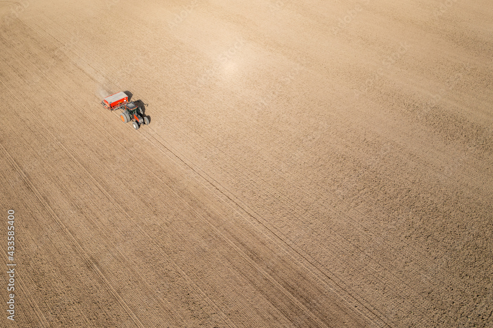 Aerial view of sowing or planting seeds with a tractor on agricultural field.