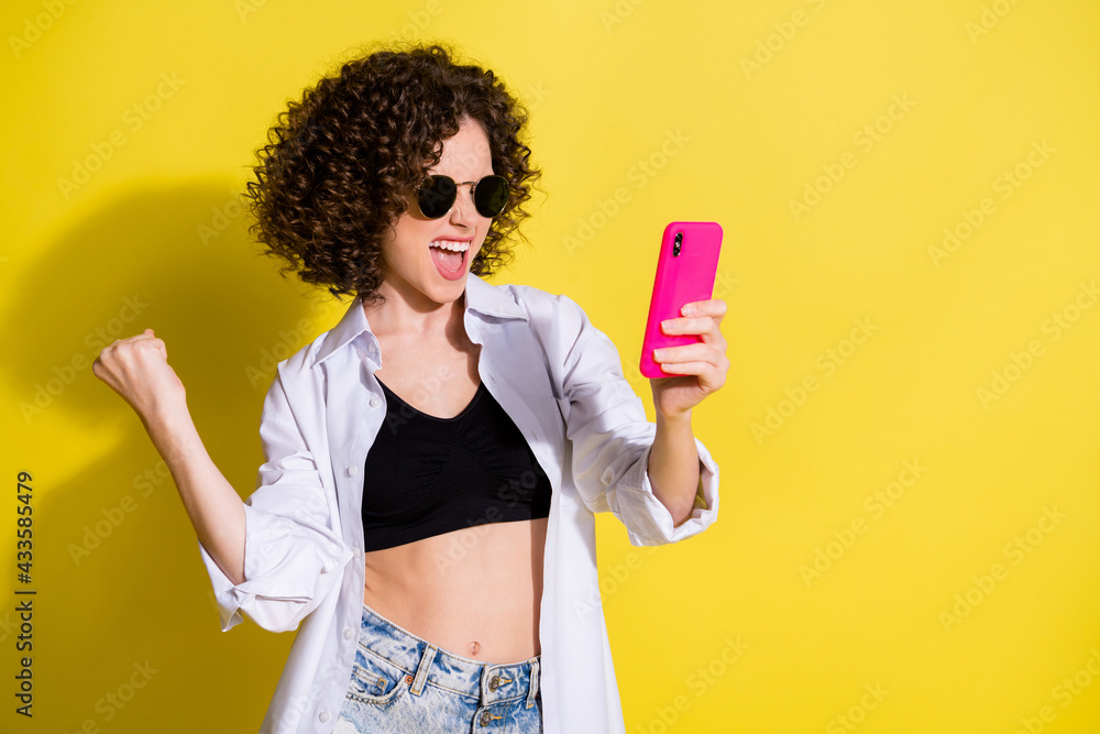 Photo portrait of female student keeping mobile phone gesturing like winner isolated on bright color background copyspace Photo portrait of female student keeping mobile phone gesturing like winner isolated on bright color background copyspace