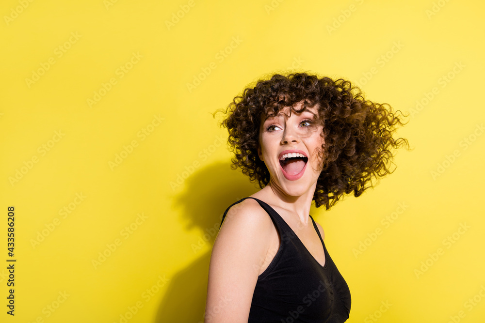 Profile portrait of nice wavy hairdo girl look back empty space open mouth wear black top isolated on yellow color background Profile portrait of nice wavy hairdo girl look back empty space open mouth wear black top isolated on yellow color background