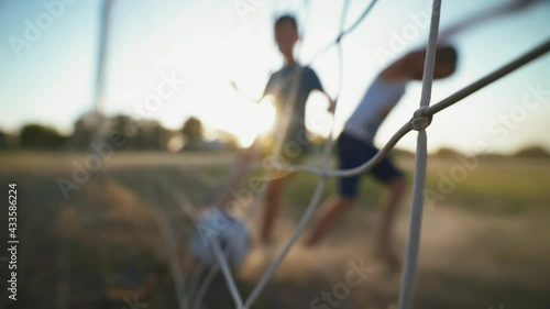 Silhouettes of children competing for ball control. Young boys are playing on a soccer field on a hot day. Football concept. Street sports in a poor area of a city or village. Training. Childhood 