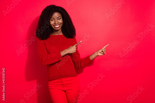 Photo of young afro girl happy positive smile point fingers empty space advert advise suggest isolated over red color background