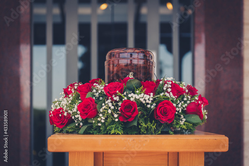 Funerary urn with ashes of dead and flowers at funeral.