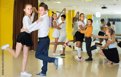 Smiling children are dancing waltz in class.