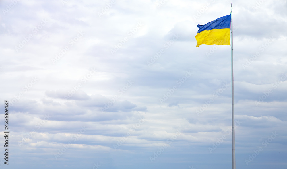 Ukraine flag against a blue sky with clouds. Banner for inserting text about the freedom and independence of European country. Ukraine flag against a blue sky with clouds. Banner for inserting text about the freedom and independence of European country.
