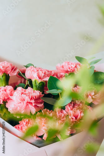 Delicate bouquet of coral carnations with eucalyptus greens with green bokeh. Summer background