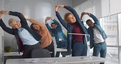 Group of happy diverse businesspeople doing stretching exercise in office