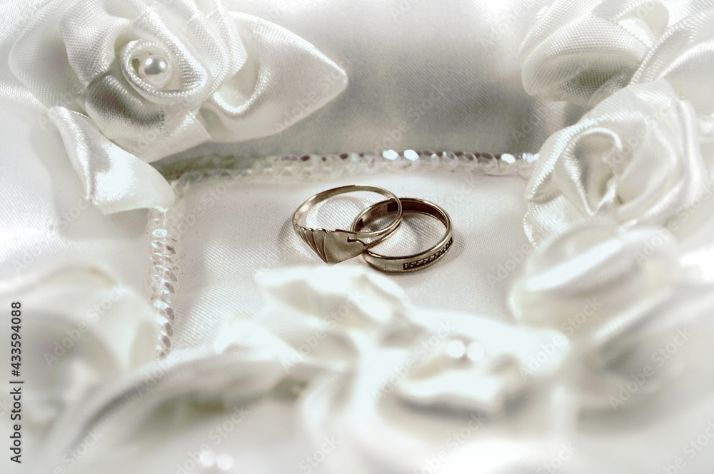 Two wedding rings on a white pillow with handmade flowers Two wedding rings on a white pillow with handmade flowers