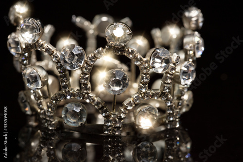 Jewelry crown with shiny stones on a black background.