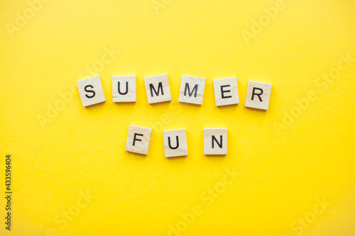 The inscription from wooden cubes summer fun on a bright yellow background. High quality photo