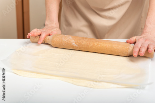 Cook rolls out the dough thinly with rolling pin. Preparing the dough for baking.