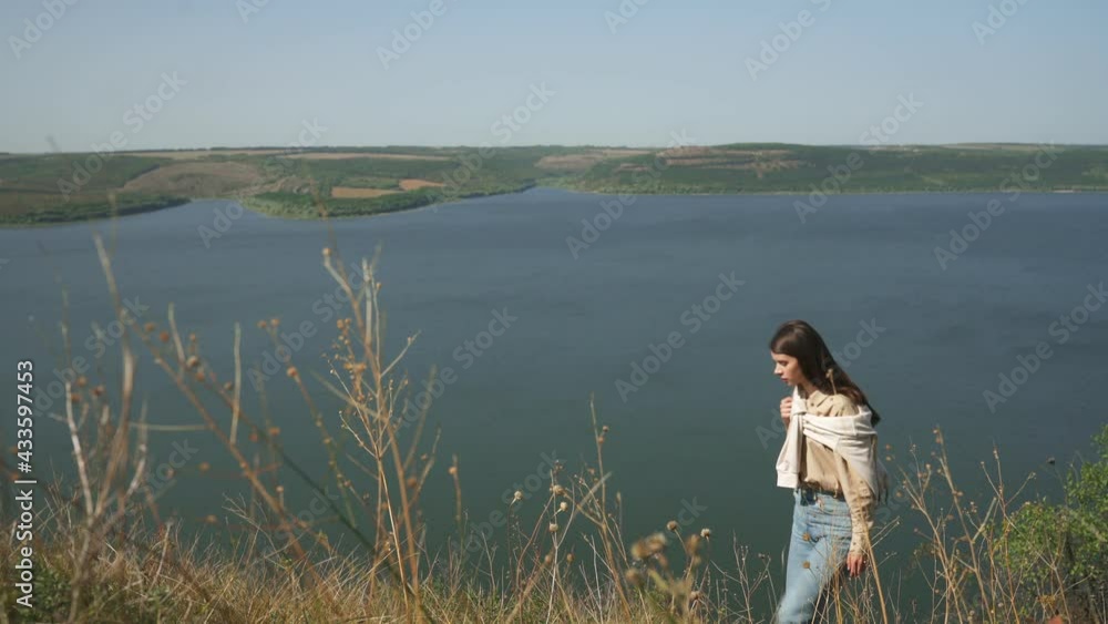 Attractive female hiker in casual wear with backpack enjoying beautiful view of Dniester river from high hill. Concept of travelling and adventure. Attractive female hiker in casual wear with backpack enjoying beautiful view of Dniester river from high hill. Concept of travelling and adventure.