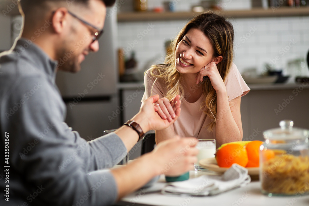 Beautiful young girl enjoying in breakfast with her boyfriend. Loving couple drinking coffee in the kitchen.