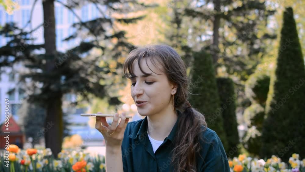 Beautiful young caucasian girl talking on the phone in a city park in summer Beautiful young caucasian girl talking on the phone in a city park in summer