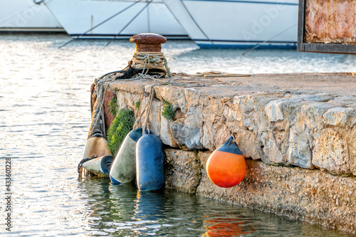 A seaport at sunset with bollard, ropes and fenders.
