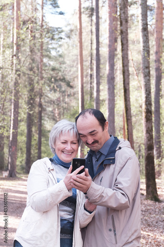 Elderly interracial couple park looking together at a mobile phone screen