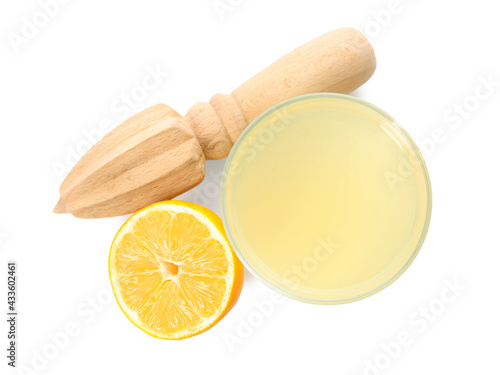 Freshly squeezed juice, half of lemon and reamer on white background, top view photo