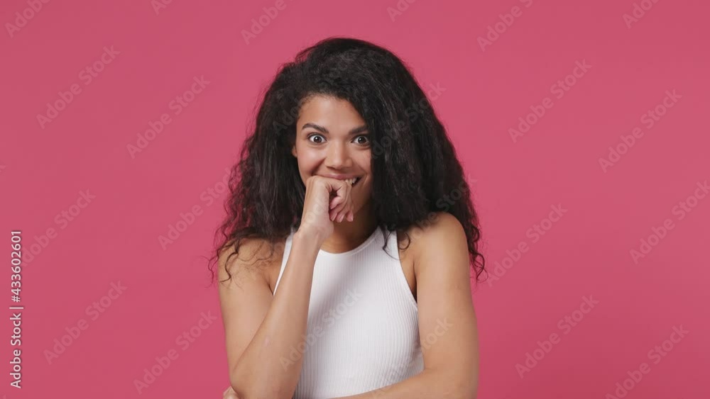 Young african woman curly hair 20s years old wears white tank top shirt ask what wow omg no way put hands on face isolated on dark pink color wall background studio. People emotions lifestyle concept Young african woman curly hair 20s years old wears white tank top shirt ask what wow omg no way put hands on face isolated on dark pink color wall background studio. People emotions lifestyle concept