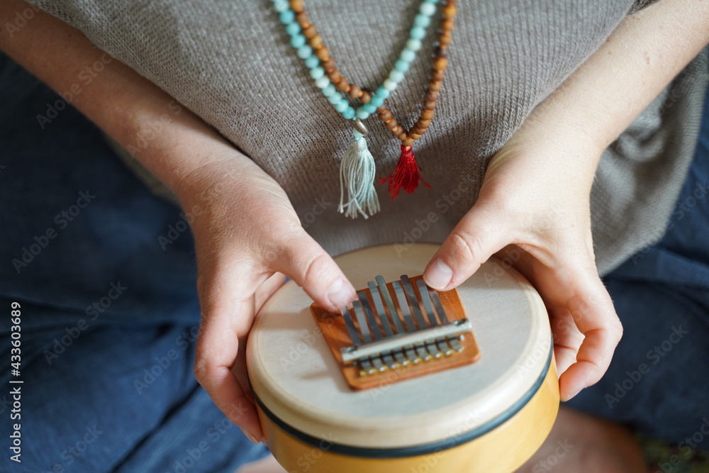 Woman holding and playing a sound healing instrument Sansula for sound healing therapy  - obrazy, fototapety, plakaty 