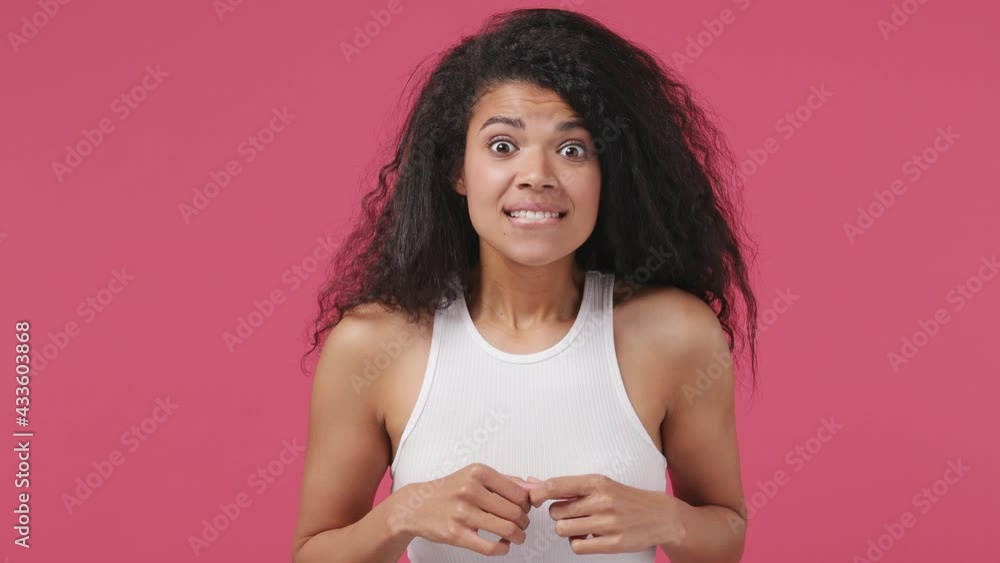 Excited sport fan young african woman wears white tank top shirt wait for special moment go celebrate win scream rejoices doing winner hands gesture at last isolated on dark pink color wall background Excited sport fan young african woman wears white tank top shirt wait for special moment go celebrate win scream rejoices doing winner hands gesture at last isolated on dark pink color wall background