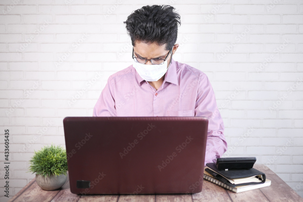 Businessman in face mask working on laptop 