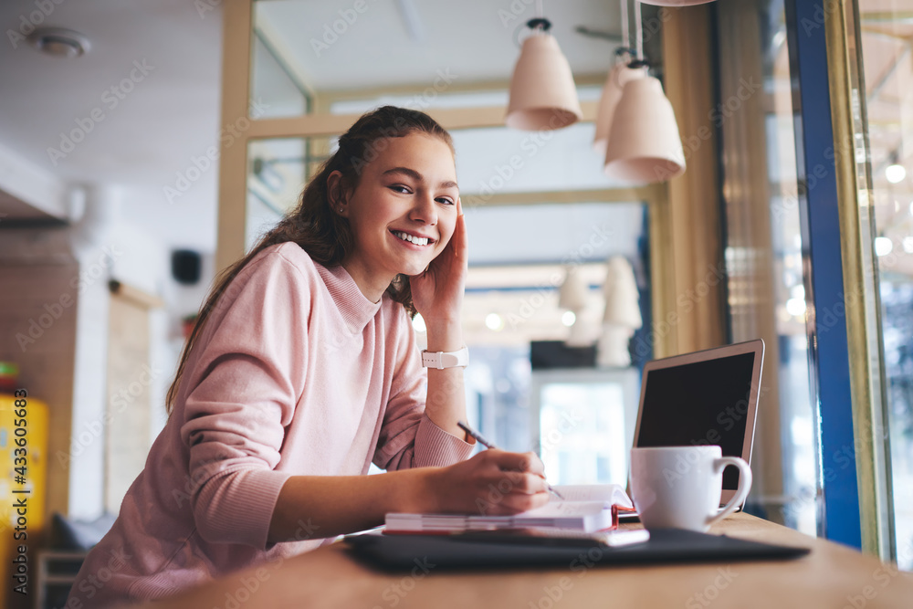 Fototapeta premium Cheerful woman writing in notebook during work