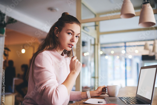 Thoughtful freelancer working at table with laptop in cafe