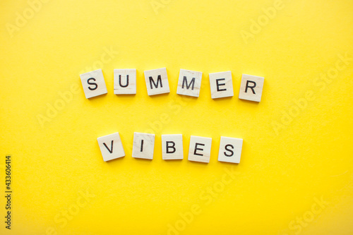 The inscription from wooden cubes summer vibes on a bright yellow background. High quality photo