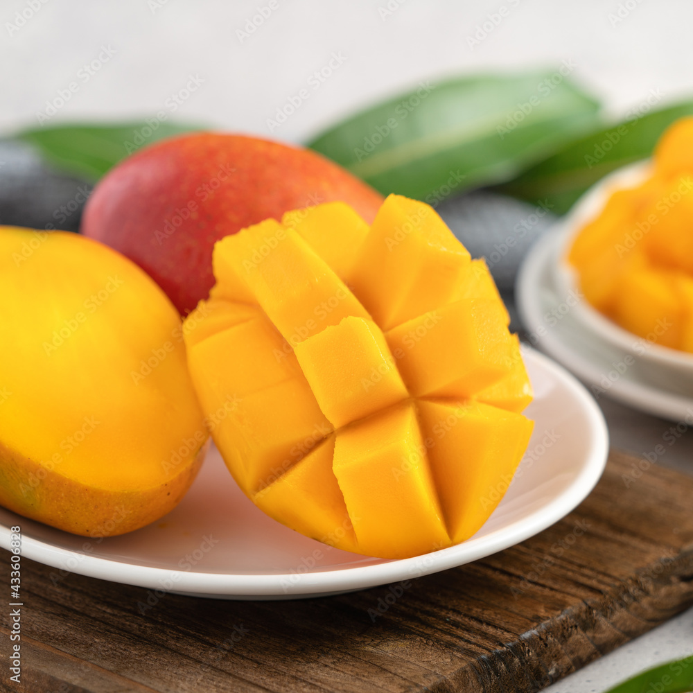 Diced fresh mango fruit on a white plate with leaves. Diced fresh mango fruit on a white plate with leaves.