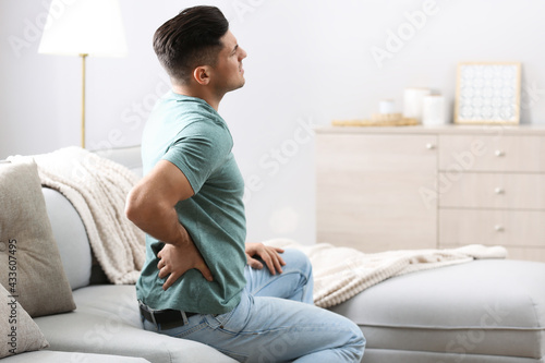 Billede på lærred Man suffering from back pain at home. Bad posture problem