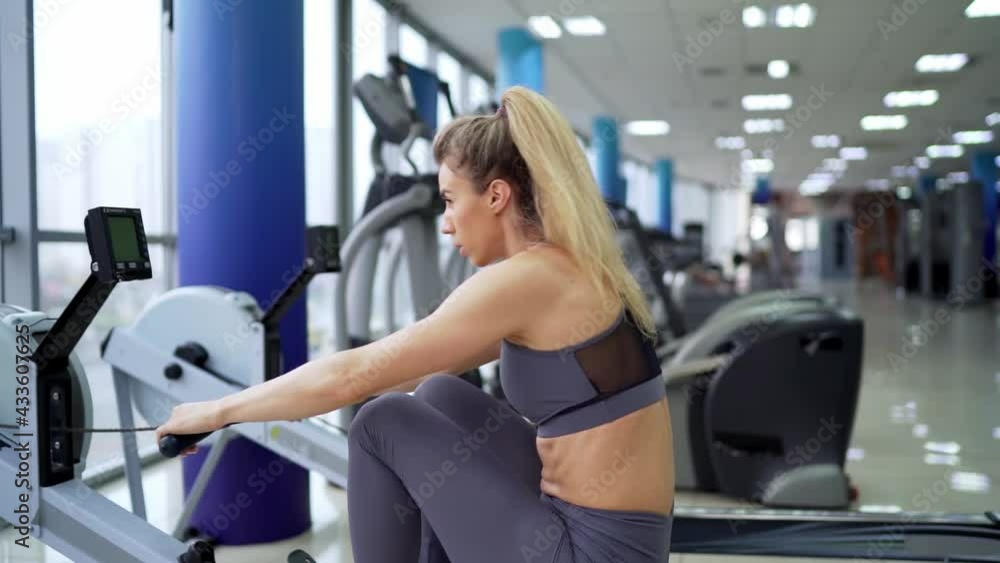 Young woman working out on row machine at gym exercising Young woman working out on row machine at gym exercising