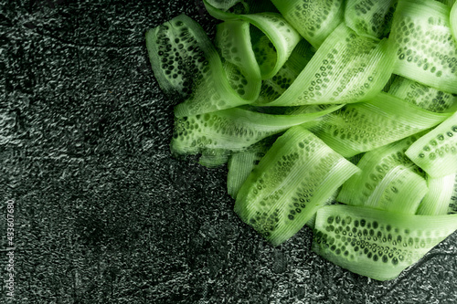 food background. sliced thin slices of fresh green cucumber. on a dark background, a rich green color. top view, macro