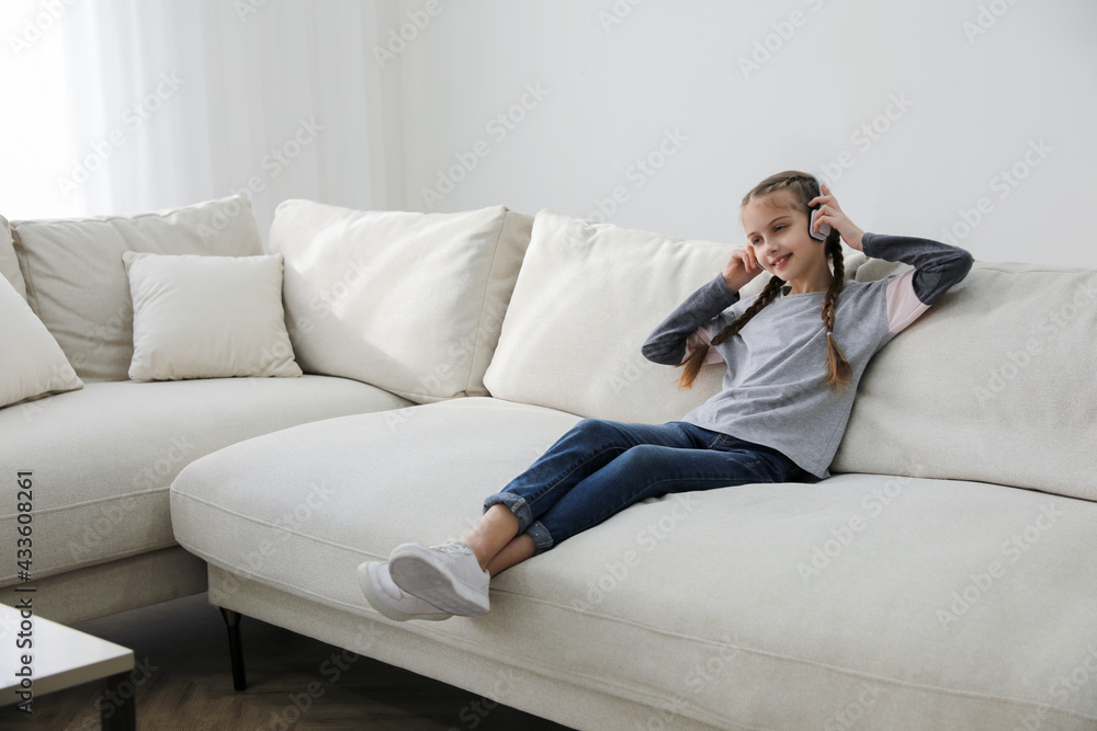 Girl with headphones sitting on comfortable sofa in living room Girl with headphones sitting on comfortable sofa in living room