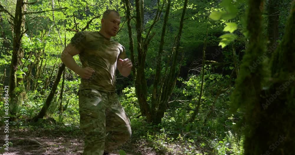 handsome brutal man sportsman jogging in the forest in special khaki clothes. handsome brutal man sportsman jogging in the forest in special khaki clothes.