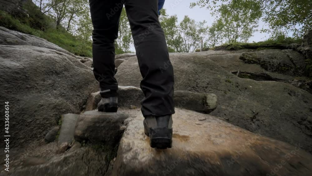 Active backpacker man fast climbing on wet stones mountain walking at rainforest Active backpacker man fast climbing on wet stones mountain walking at rainforest