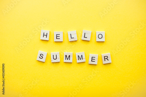 The inscription from wooden cubes hello summer on a bright yellow background. High quality photo