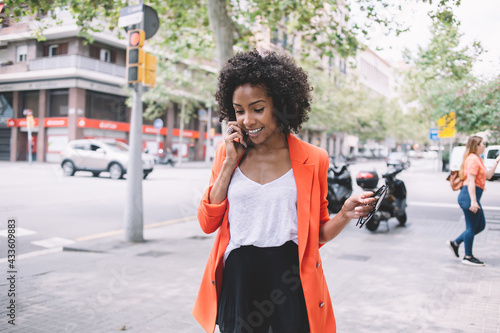 Young ethnic woman speaking on phone in street