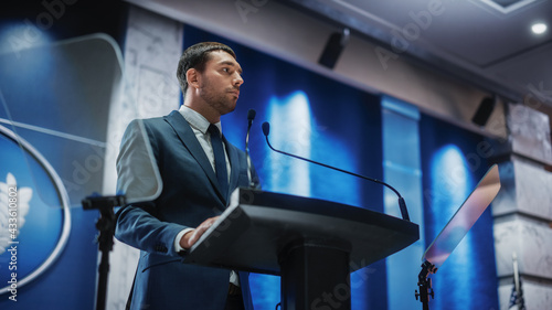 Portrait of an Young Organization Representative Speaking at Press Conference in Government Building. Press Officer Delivering a Speech at Summit. Minister Speaking at Congress Hearing.