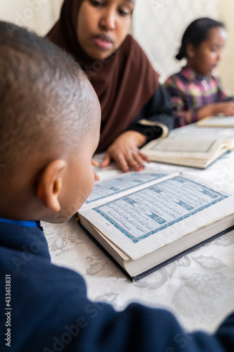 Black Muslim mother reading quran with her children