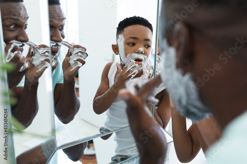 African american father and son in bathroom, applying shaving foam photo